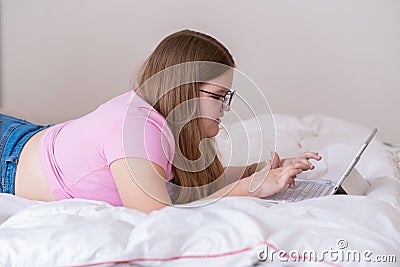 Focused overweight teen girl using touchpad of wireless keyboard to study on tablet Stock Photo