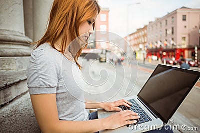 Focused pretty redhead typing on laptop Stock Photo