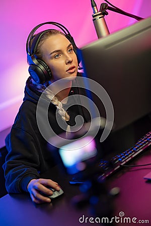 Focused Professional E-sport Gamer Girl with Headset Streaming Online Video Game on PC Stock Photo