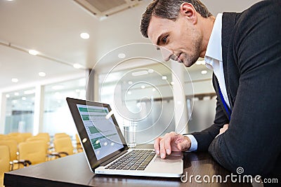 Focused serious business man working with laptop in conference hall Stock Photo