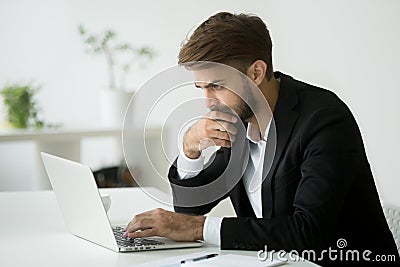 Focused serious businessman thinking reading online news using l Stock Photo