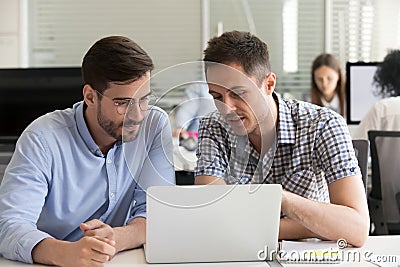 Focused serious male coworkers talking working together on compu Stock Photo