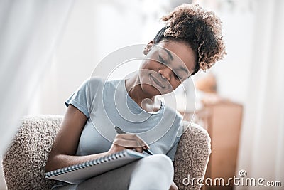 Focused smiling darkskinned woman writing at home Stock Photo