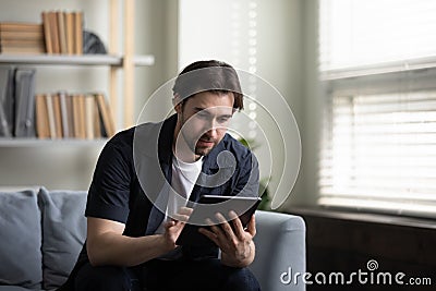 Focused tablet user man browsing internet, using online application Stock Photo