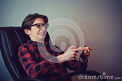 Focused teen boy playing video games late night seated in his chair. Angry and furious guy nerd wearing glasses, holding the Stock Photo