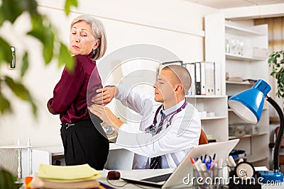 Therapist examining female patient complaining of low back pain Stock Photo