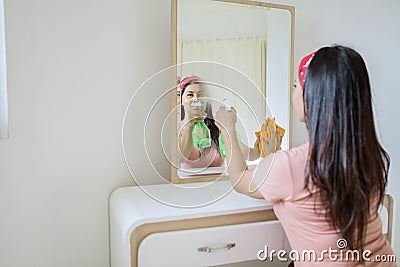 Focused view of beautiful woman spraying a mirror Stock Photo