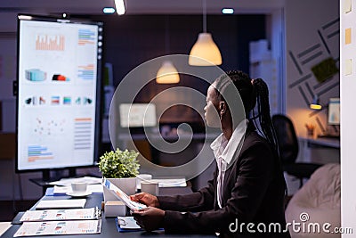 Focused workaholic african american businesswoman working at company financial charts presentation Stock Photo