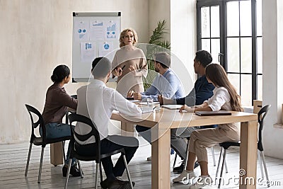 Focused young diverse employees listening to older 60s team leader. Stock Photo