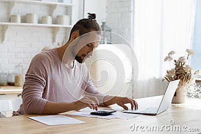 Focused young man managing household budget alone at home. Stock Photo