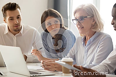 Focused young interns making notes listening to old female manager Stock Photo