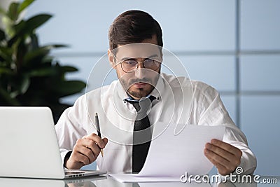 Focused young motivated businessman reading document at office. Stock Photo