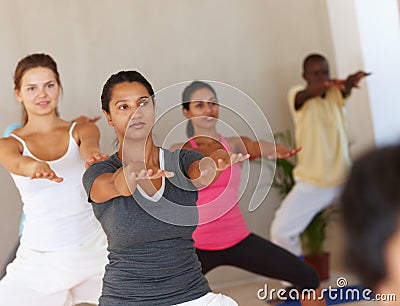 Focusing the mind and body. a group of yoga students focusing on their form during class. Stock Photo