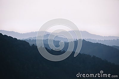 Fog covering the mountain forests. The atmospheric silhouettes of mountains in blue color Stock Photo