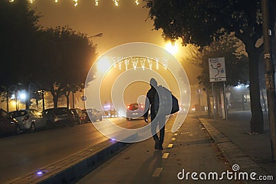 Foggy, christmas night scene, man carrying sack on his shoulders walking on the street Editorial Stock Photo