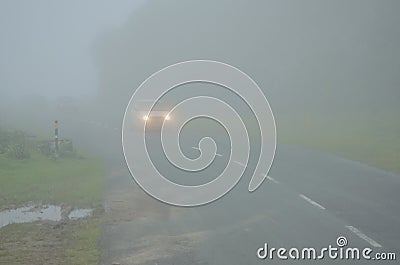 Foggy landscape of road and car moving with headlights turned on. Densely mist in the winter by clouds Stock Photo