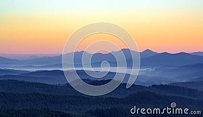 Foggy morning in the mountains with silhouettes of hills. Serenity sunrise with soft sunlight and layers of haze Stock Photo