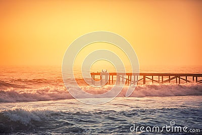 Foggy morning over the sea. Seagulls standing at old broken bridge in the water. Stock Photo
