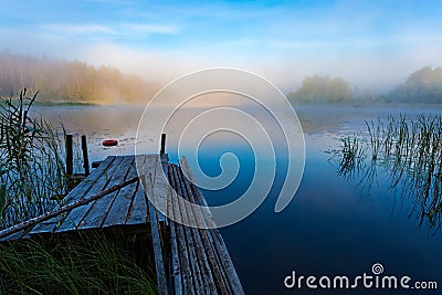 Foggy morning on the river. Lifebuoy and old broken footbridge on a quiet lake Stock Photo