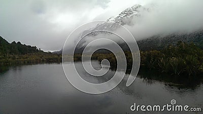 Foggy mystic morning on a lake close to Milford Sound, snow capped mountain Stock Photo
