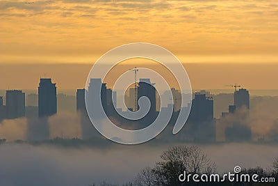 Foggy view of the morning city. Fiery dawn in Kiev. Buildings in the fog Stock Photo