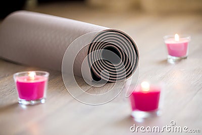 Folded brown yoga, pilates mat on the floor with lighted rose ca Stock Photo