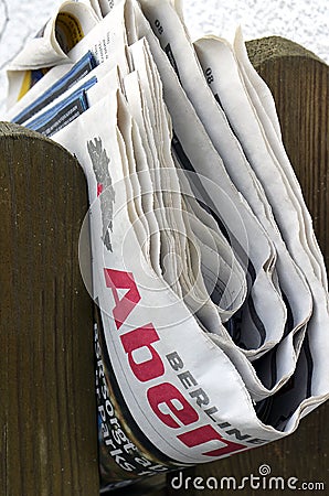 Folded newspaper clamped between pickets of a wooden fence Editorial Stock Photo