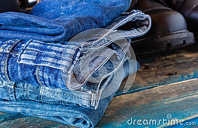 Blue jeans and leather shoes. Folded pants on old boards. Black work shoes. Stock Photo