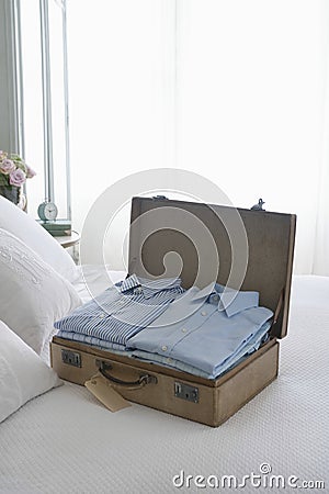 Folded Shirts In Open Suitcase On Bed Stock Photo