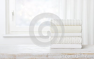 Folded sweater stack on table over blurred window with space Stock Photo