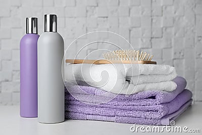 Folded towels, hair brush and shampoo on table Stock Photo