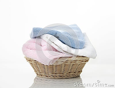 Folded towels stack in basket on white background,heap of colorful laundry on table Stock Photo