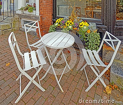 folding chairs and round table outdoor seating, brick sidewalk in Fall at restaurant Stock Photo