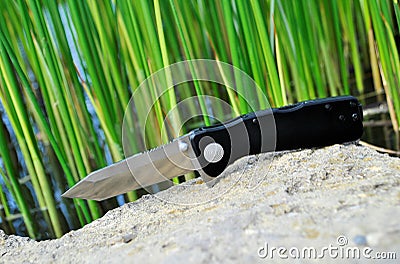 Folding knife stainless steel sharp blade black handle close up still life green background Stock Photo