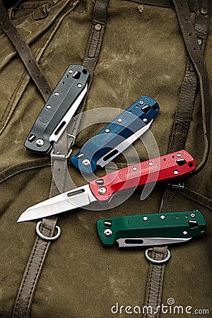 Folding multitool penknives on a khaki canvas backpack. A pocket-sized tool for hiking and daily life Stock Photo