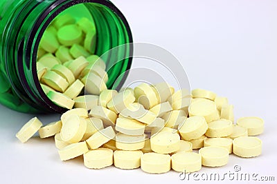 Folic acid spilling from green pill bottle Stock Photo