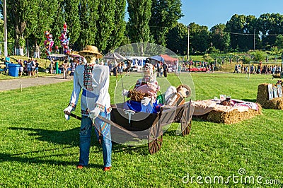 Folk festivities in honor of harvest. Models of people in national clothes and an old wooden cart. A holiday in the Editorial Stock Photo