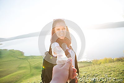 Follow me, Attractive brunette girl holding hands with leads in mountain valley Stock Photo