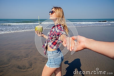 Follow me concept. girlfriend leading man holding hand. Happy woman holding coconut. Couple in love walking on tropical Stock Photo