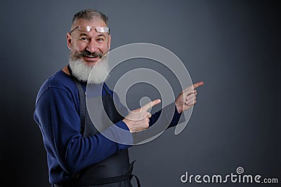 Follow me. Look here. Close up portrait of cheerful pleased qualified experienced joyful apron-wearing grandfather Stock Photo