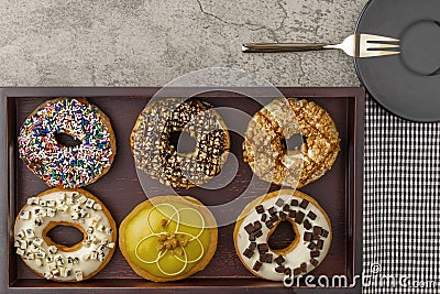 Assortment of donuts on wooden tray with napkin fork and small plate Stock Photo