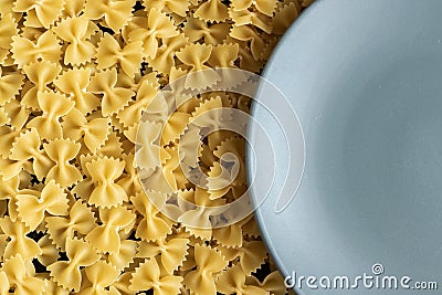 Food background - dry farfalle pasta on grey plate, whole wheat uncooked ingredient Stock Photo