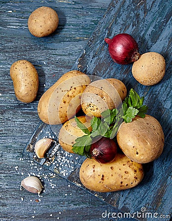 Food banner. Raw potatoes , onions , parsley on a dark wooden table Stock Photo