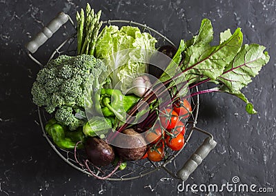 Food basket with fresh garden vegetables - beets, broccoli, eggplant, asparagus, peppers, tomatoes, cabbage on a dark table Stock Photo
