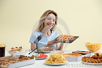 Food blogger eating in front of microphone at table against light background. Mukbang vlog Stock Photo