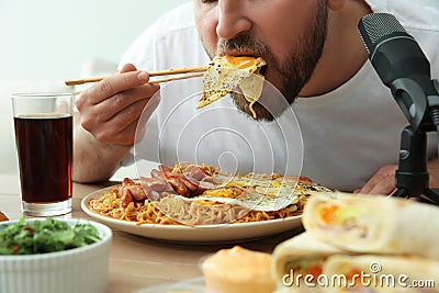 Food blogger eating in front of microphone at table. Mukbang vlog Stock Photo