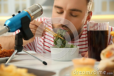 Food blogger eating near microphone at table in kitchen, closeup. Mukbang vlog Stock Photo