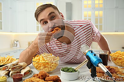 Food blogger eating near microphone at table in kitchen. Mukbang vlog Stock Photo
