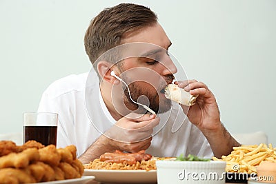Food blogger eating at table against light background Stock Photo