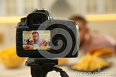 Food blogger recording eating show in kitchen, focus on camera screen. Mukbang vlog Stock Photo